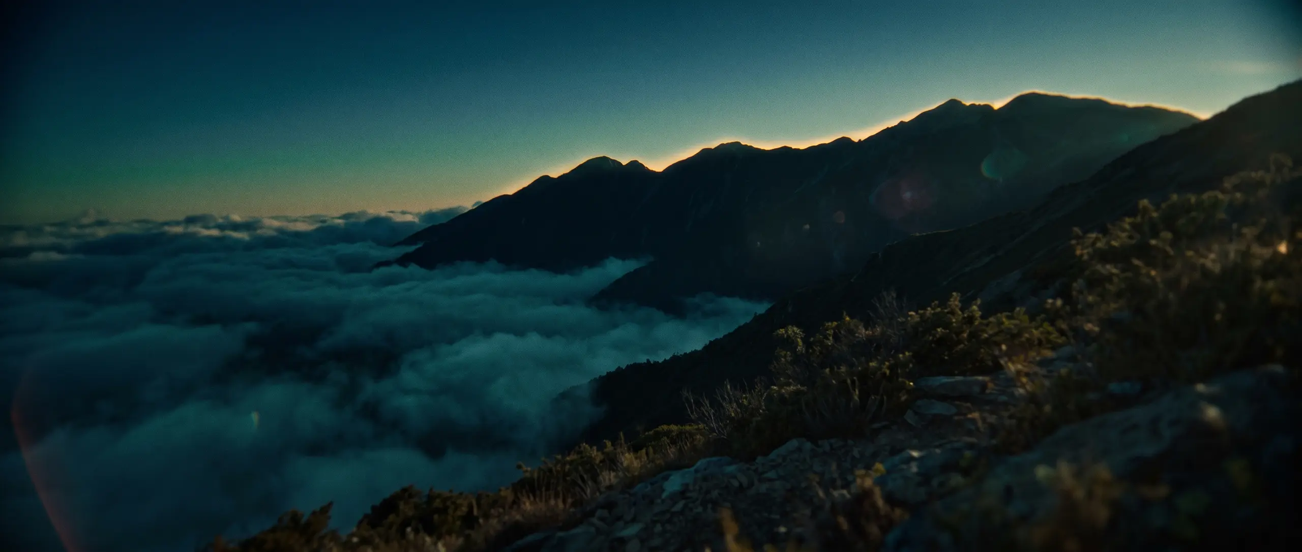A ridgeline above a sea of cloud, first light breaking along the crest